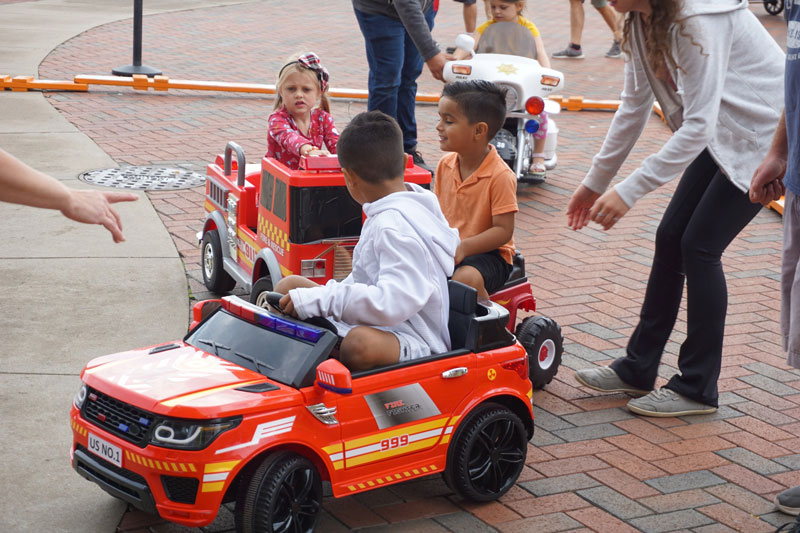 Children riding on battery operated fire vehicles on a beautiful fall day at Touch a Truck held at the Leach Amphitheater