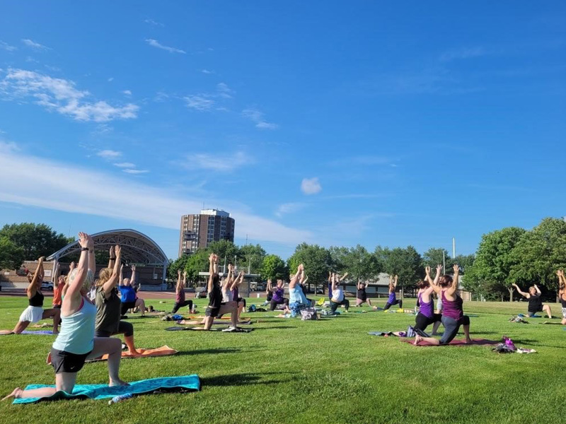 A group of people participating in Yoga at the Leach Amphitheater ran by Simply Yoga on a sunny evening during the summer